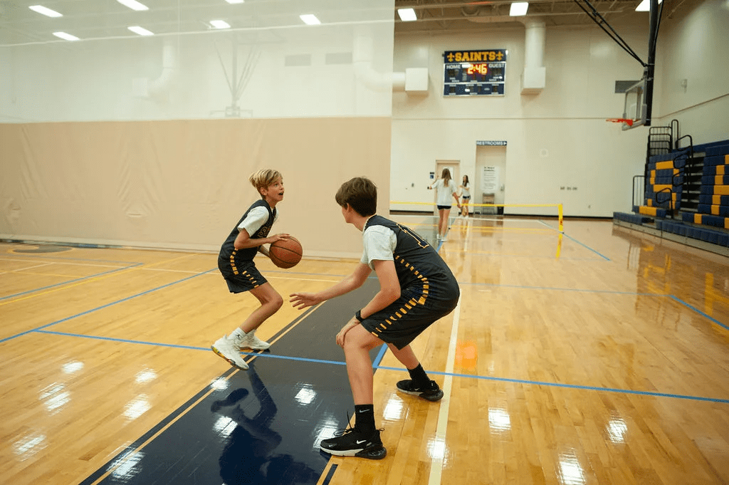 Two boys playing basketball in the gym.
