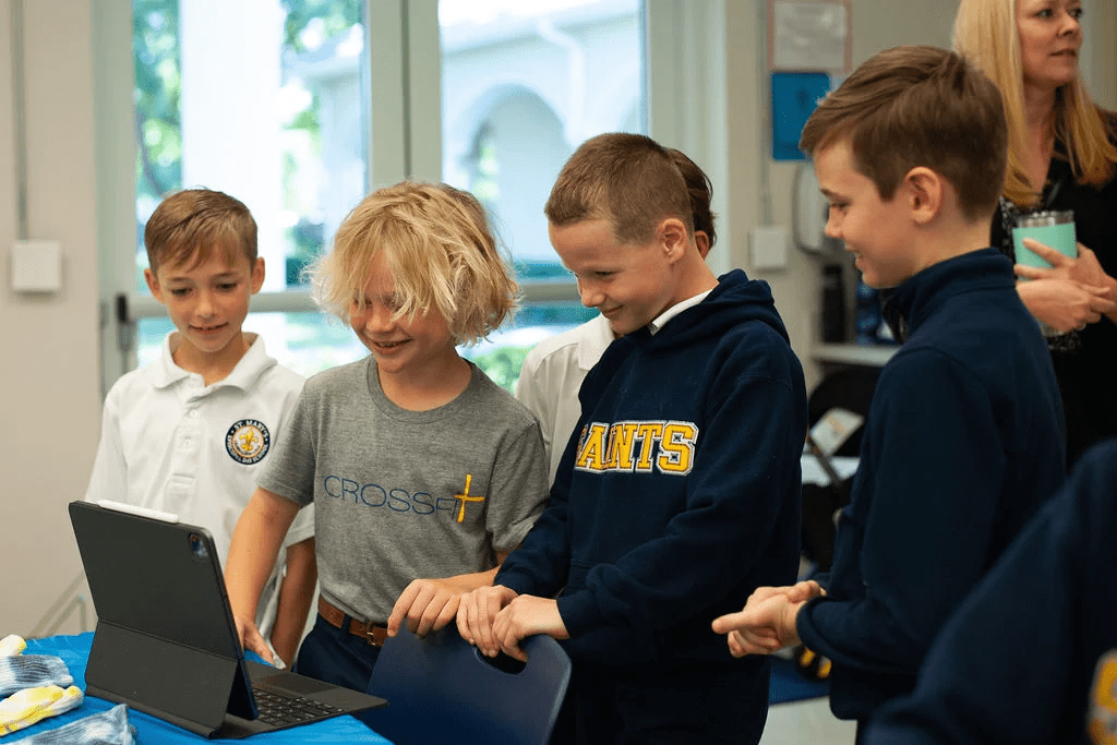 Four boys standing around a laptop smiling.