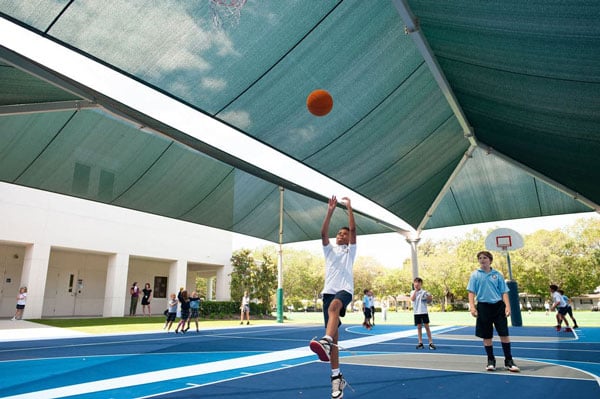 A student shooting a basketball outside.