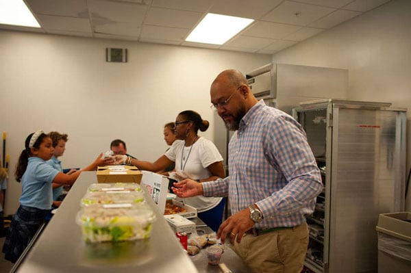 Faculty handing out food in the school cafeteria.