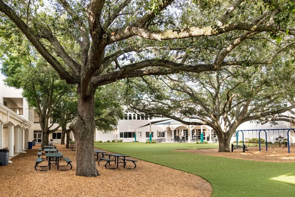A courtyard with an outside eating area, and a building in the background.