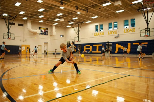 A student playing pickle ball inside the gym.