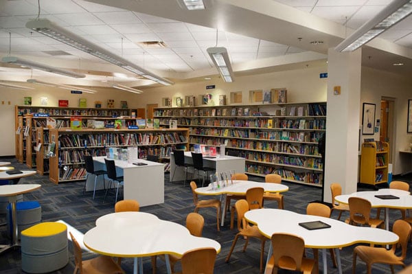 A library with cloud shaped tables, bookshelves, and chairs.