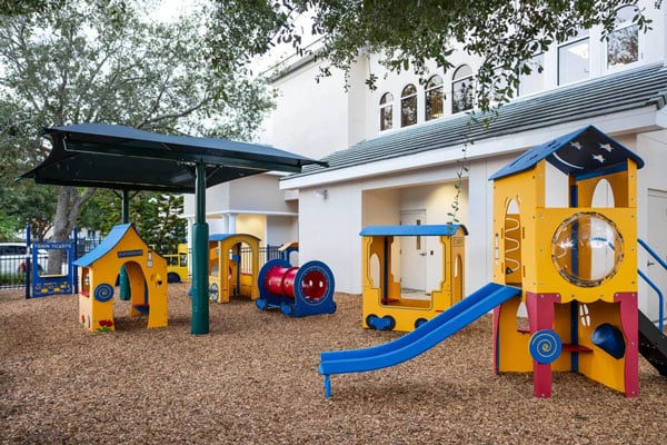 A playground showcasing yellow playhouses and a blue slide.