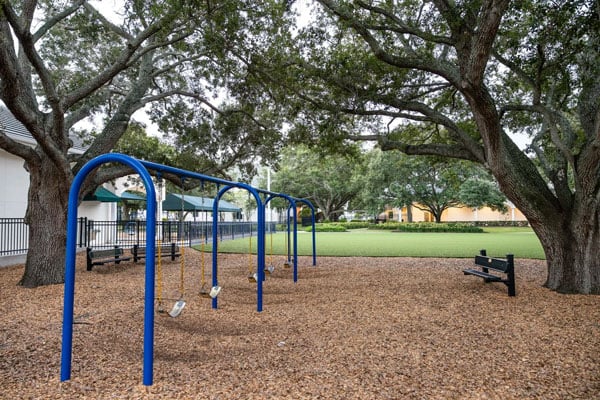 A section of a playground showcasing a bench and blue swings.