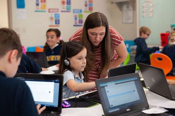 A classroom of lower school students doing an activity on laptops.