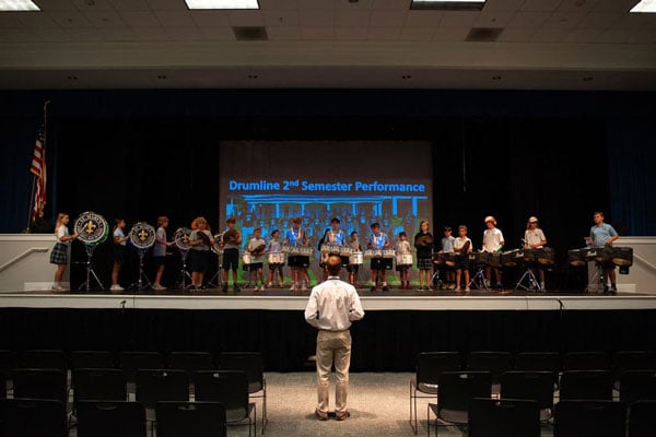 The drumline playing songs inside of the campus theater.