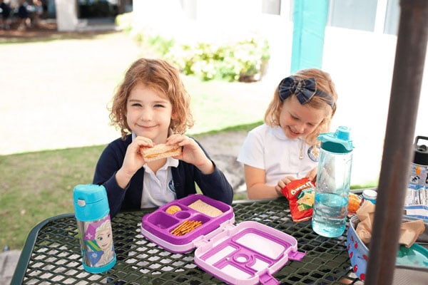 Two girls eating their lunch outside.