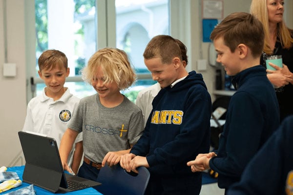 A group of four male students smiling at an iPad.