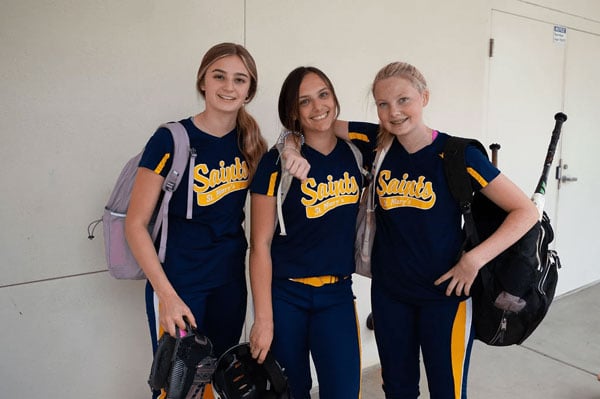 Three female students in their softball uniform.